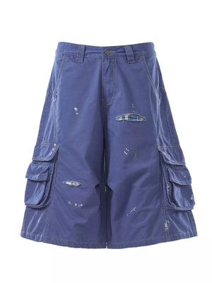 Blue distressed cargo capris with multiple pockets and plaid patch detail.