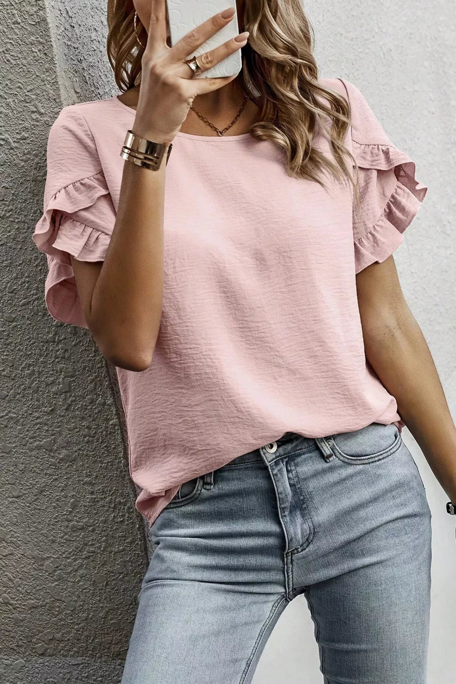 Blush pink polyester blouse with ruffle trim short sleeves and a textured finish.
