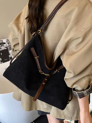 Black suede tote bag with brown leather trim and straps.