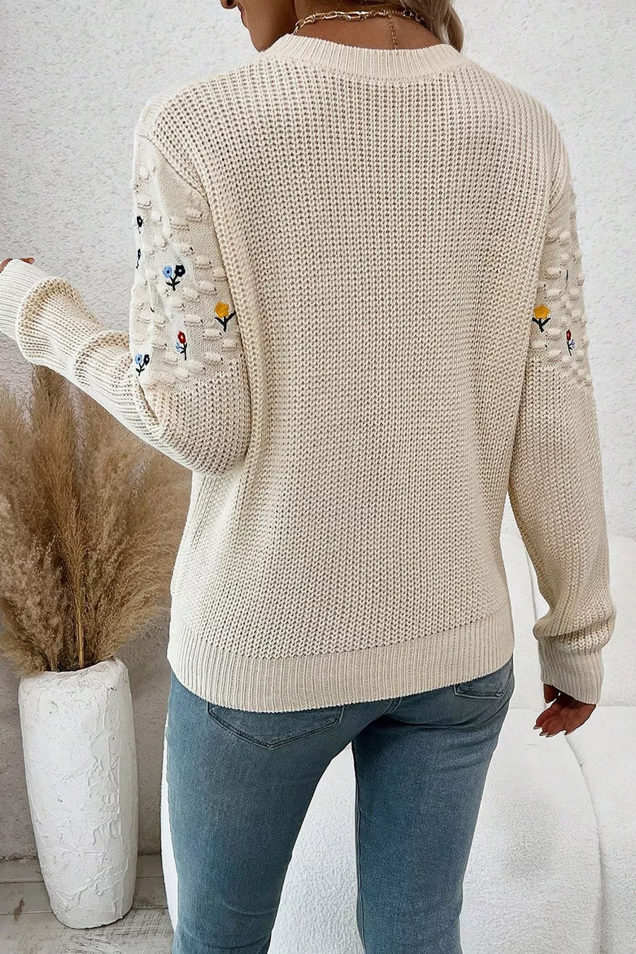 Beige embroidered round-neck sweater with dropped shoulders and textured sleeves.