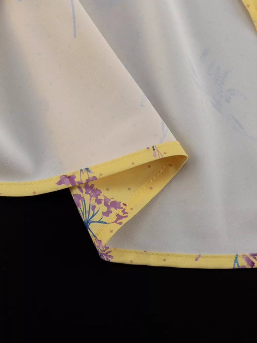 Yellow floral print blouse with a subtle polka dot pattern and contrasting trim.