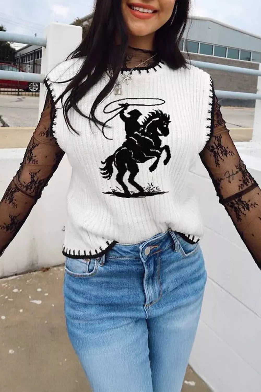 White knit sweater vest with black rodeo graphic and contrast trim, worn over black lace sleeves.