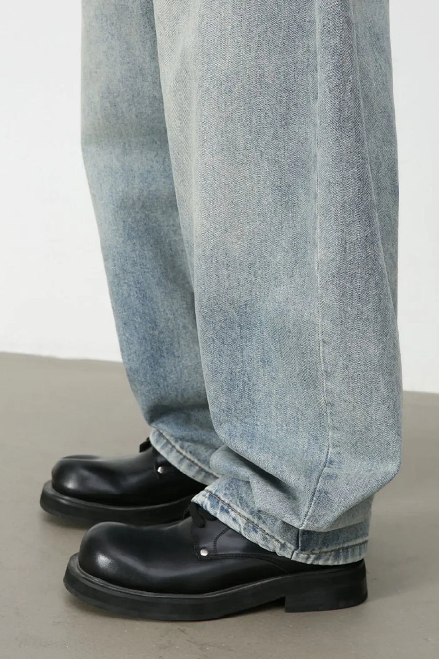 Faded light blue baggy denim jeans with a relaxed fit, styled with black chunky shoes.