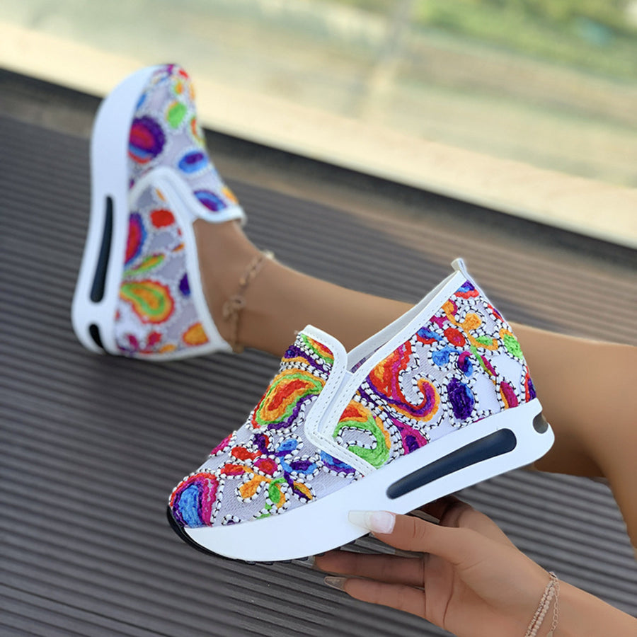 Vibrant slip-on platform sneakers with colorful paisley embroidery and white soles.
