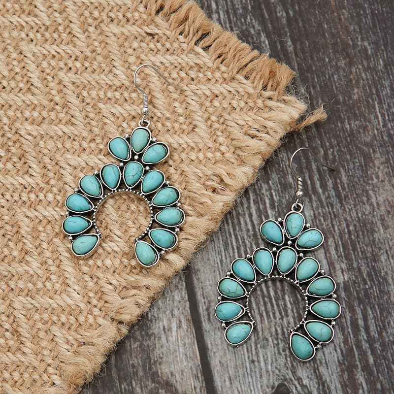 Teal crescent dangle earrings with turquoise stones and silver alloy metal.