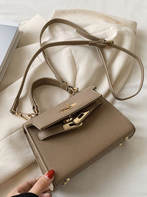 Khaki mini crossbody bag in faux leather with gold hardware and a top handle.