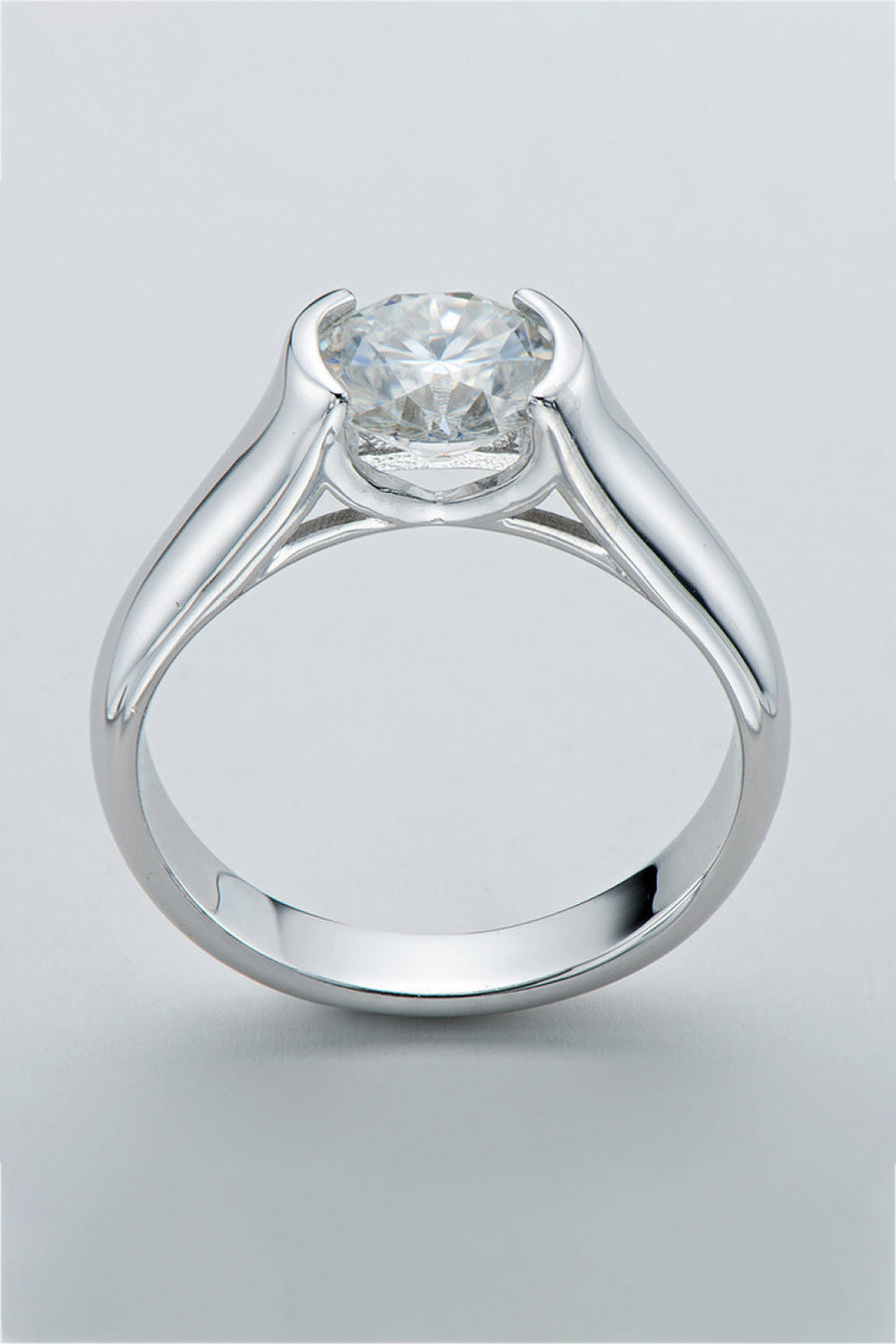 Silver platinum ring with a bezel-set round moissanite solitaire diamond.