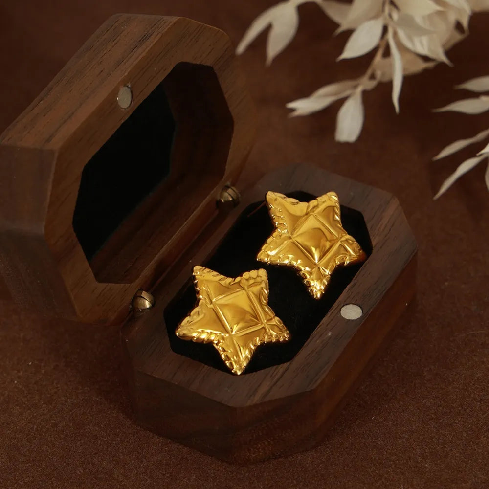 Textured gold star stud earrings with celestial pattern in a wooden box.