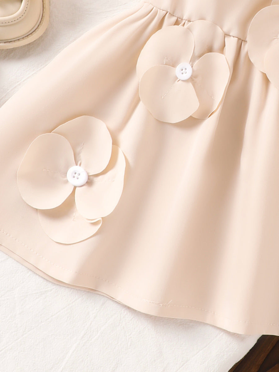 Off-white baby dress with 3D flower appliqués and white buttons.