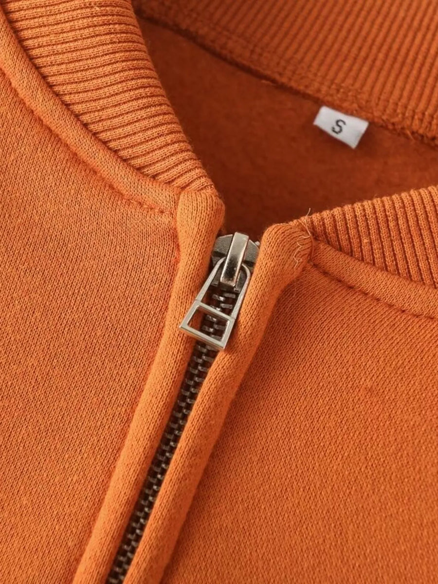 Orange casual zip-up top detail with silver zipper and size S tag.