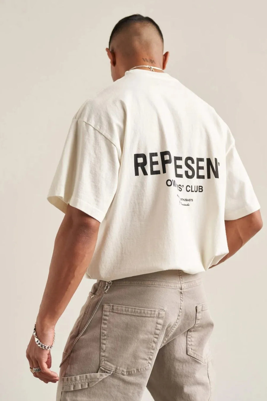 Oversized ivory graphic tee with black "REPESENT OWNERS' CLUB" text on back.