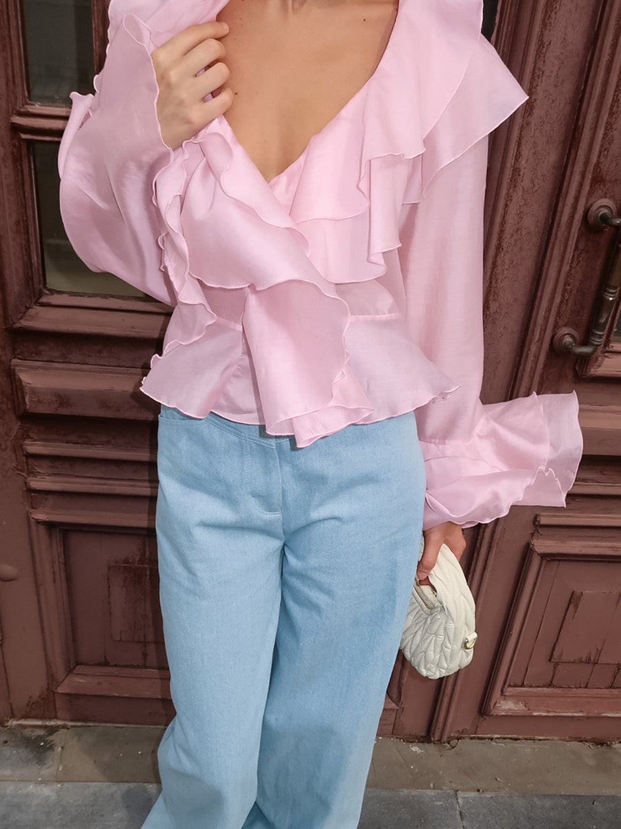 Pink ruffle trim long sleeve blouse with dramatic sleeves and a deep V-neckline.