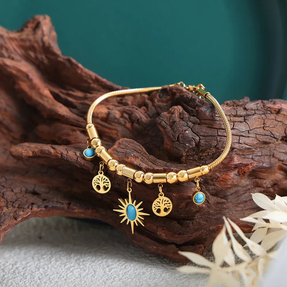 Gold bracelet with turquoise accents, featuring tree of life and sun charms