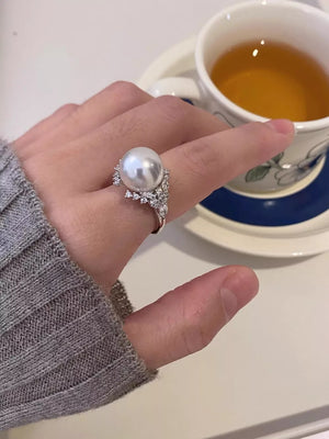 Luminous pearl and silver ring with sparkling accents on a woman's hand.