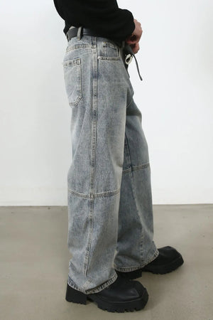 Baggy distressed medium wash cargo jeans with paneling detail.