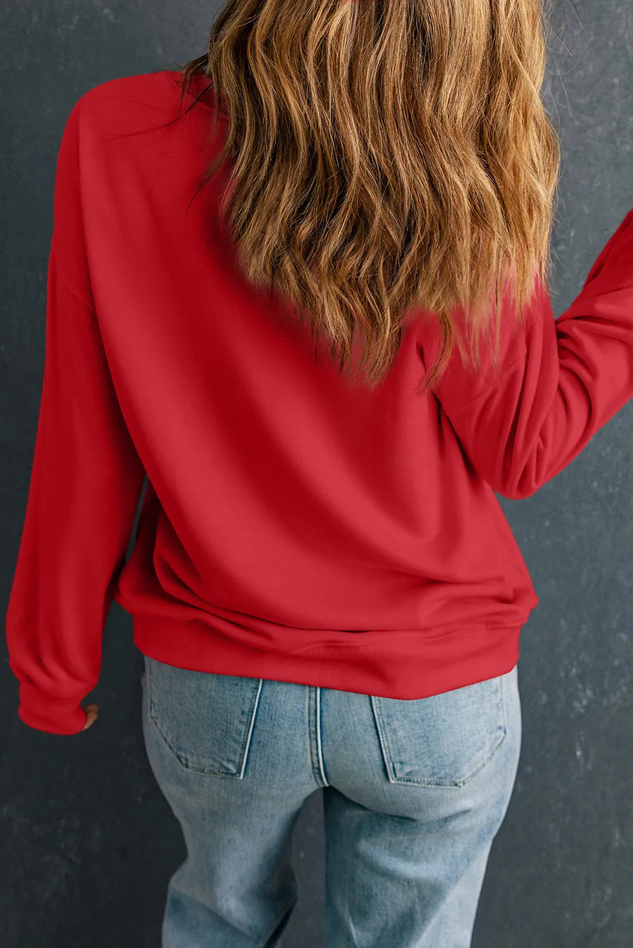 Scarlet red crewneck sweatshirt with long sleeves, casual fit, paired with denim jeans.