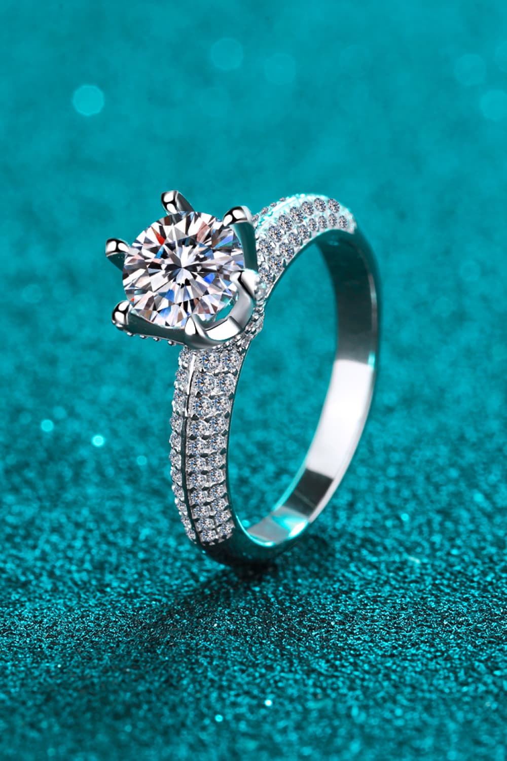 Silver pavé halo moissanite solitaire ring with a round cut center stone.