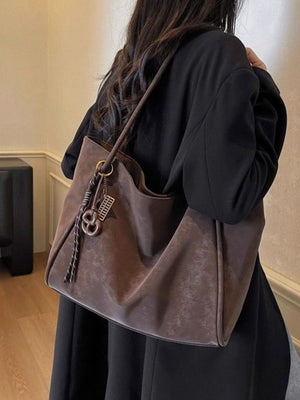 Brown suede shoulder bag with braided rope strap and metal charm detail