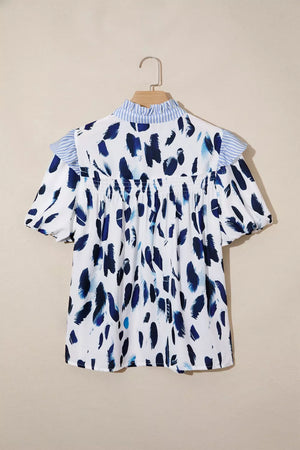 White polyester shirt with abstract blue brushstroke print, ruffled collar, and short sleeves.