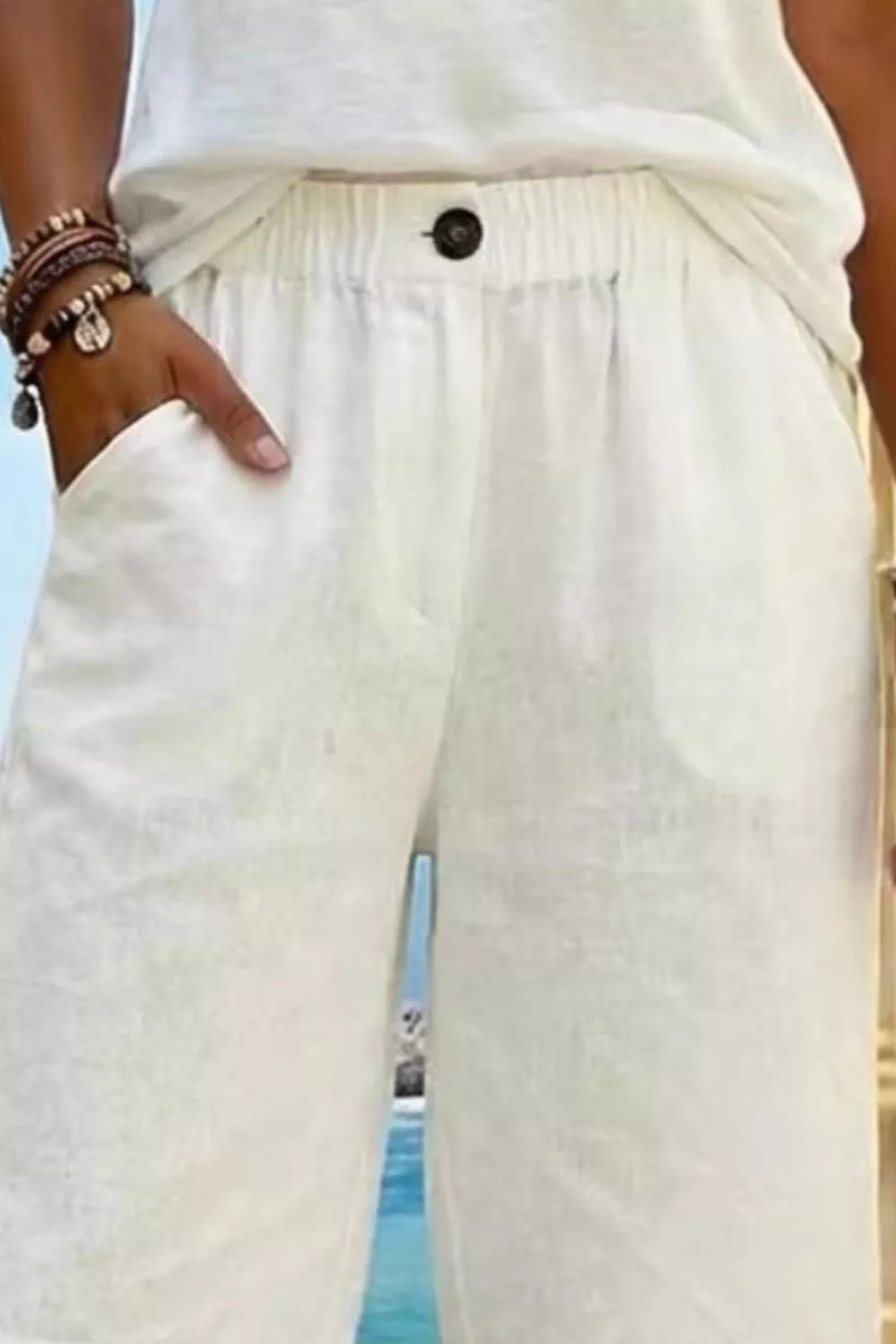 White pocketed knee-length shorts with elastic waist and button detail.