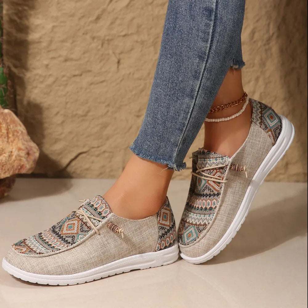Embroidered canvas slip-on flats in Tan with tribal pattern and rope detail.