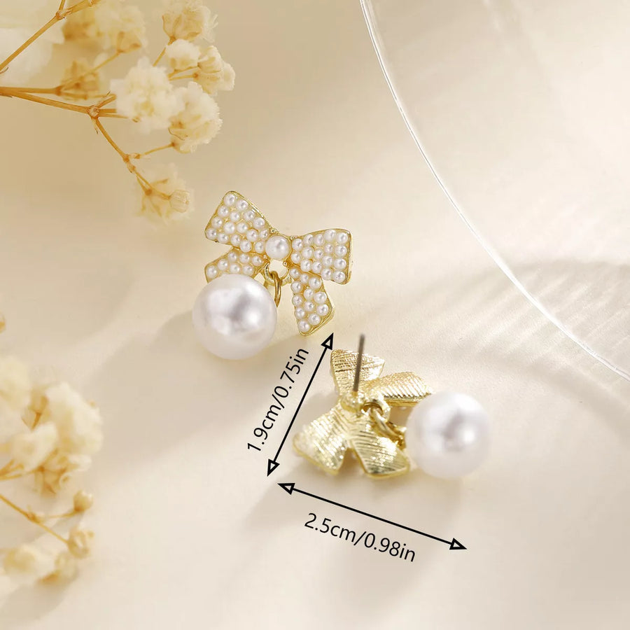 Gold bowknot pearl drop earrings with pearl accents and a dangling pearl.