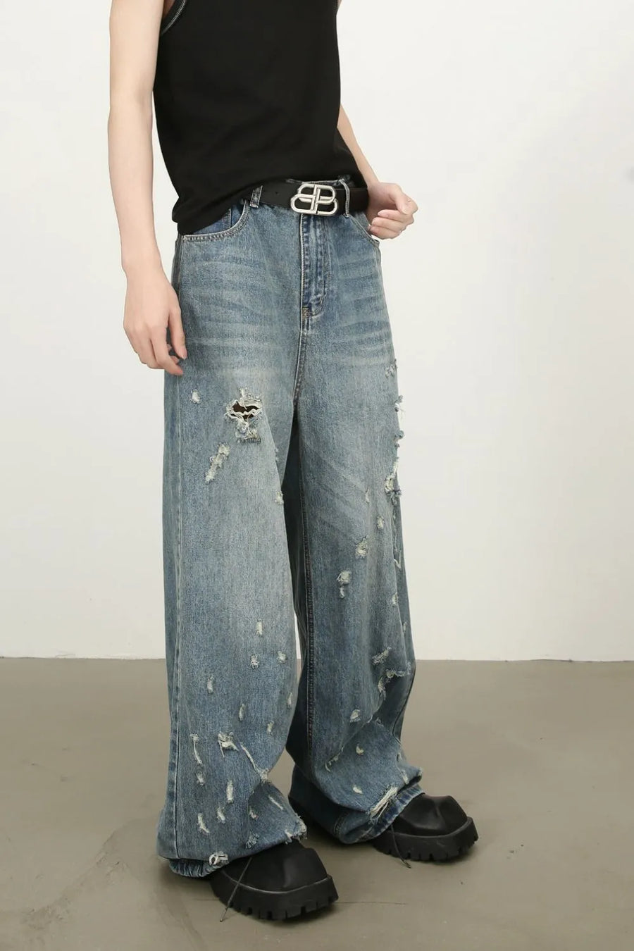 Distressed palazzo jeans in medium wash denim with raw edge detail and ripped accents.