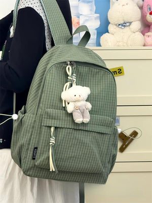 Green plaid medium nylon backpack with teddy bear charm and tassel detail.
