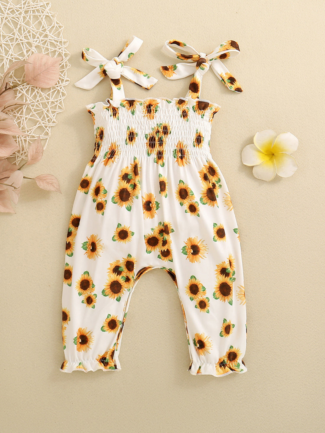 Baby white cotton jumpsuit with allover sunflower print, smocked bodice and tie straps.