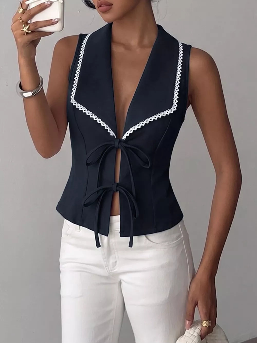 Navy lace-trimmed tie-front vest with a deep V-neck and open front styled with white jeans.