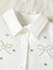 White baby girls' top with pearl bow and rhinestone embellishments.