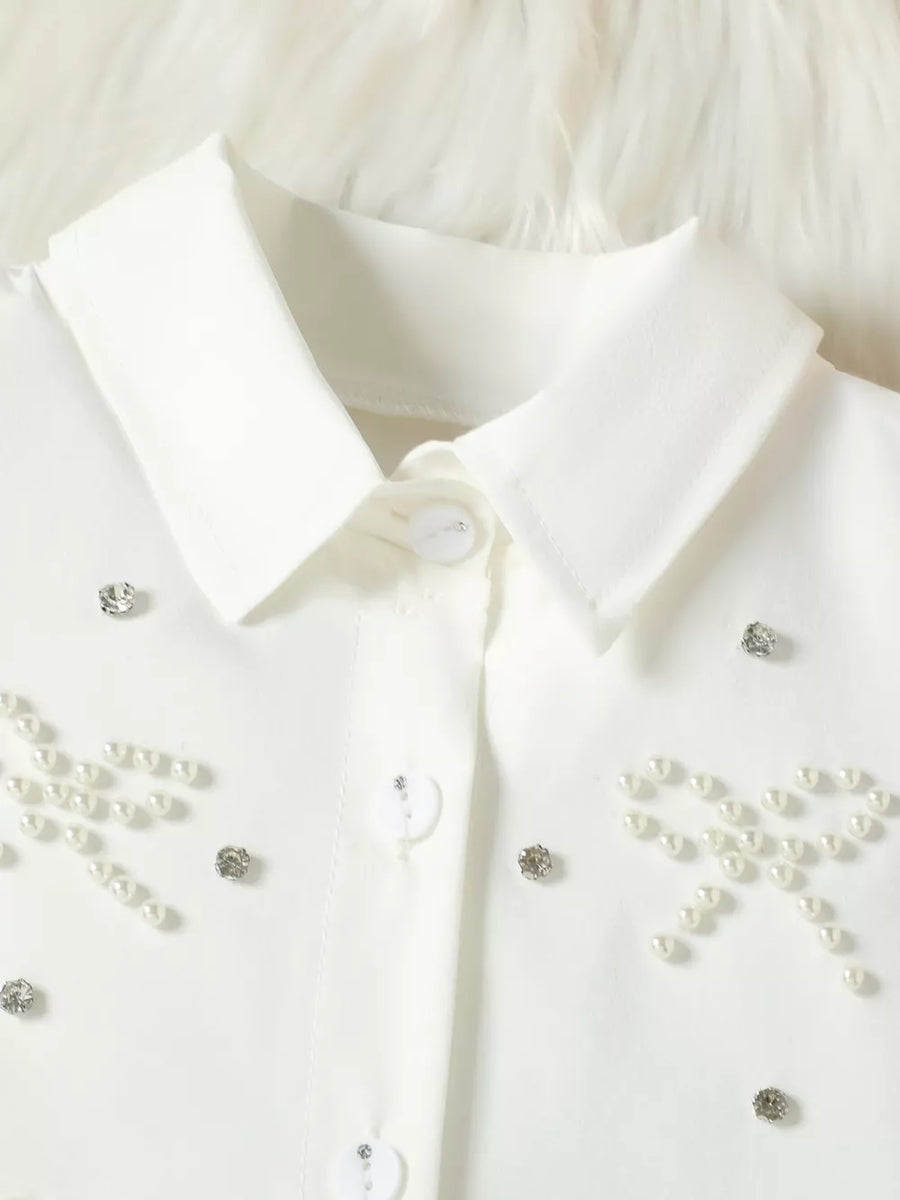 White baby girls' top with pearl bow and rhinestone embellishments.