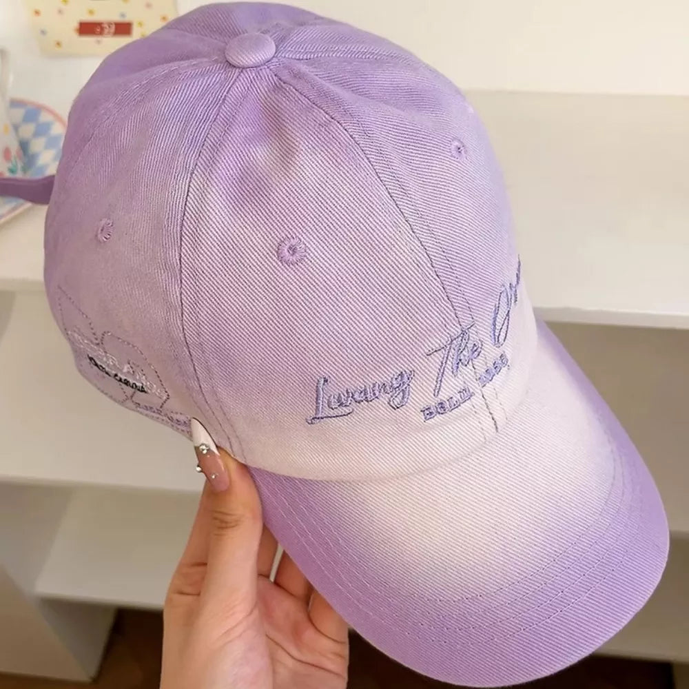 Purple and white ombre cotton baseball cap with embroidered text and graphic detail.