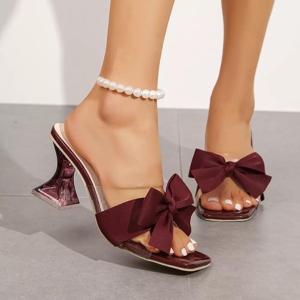 Burgundy bow open-toe sandals with clear block heels and a pearl anklet.