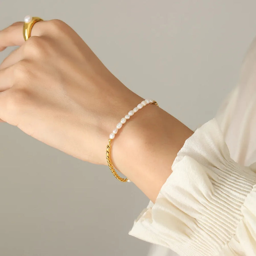 Gold bracelet with delicate pearls and chain detail on a woman's wrist