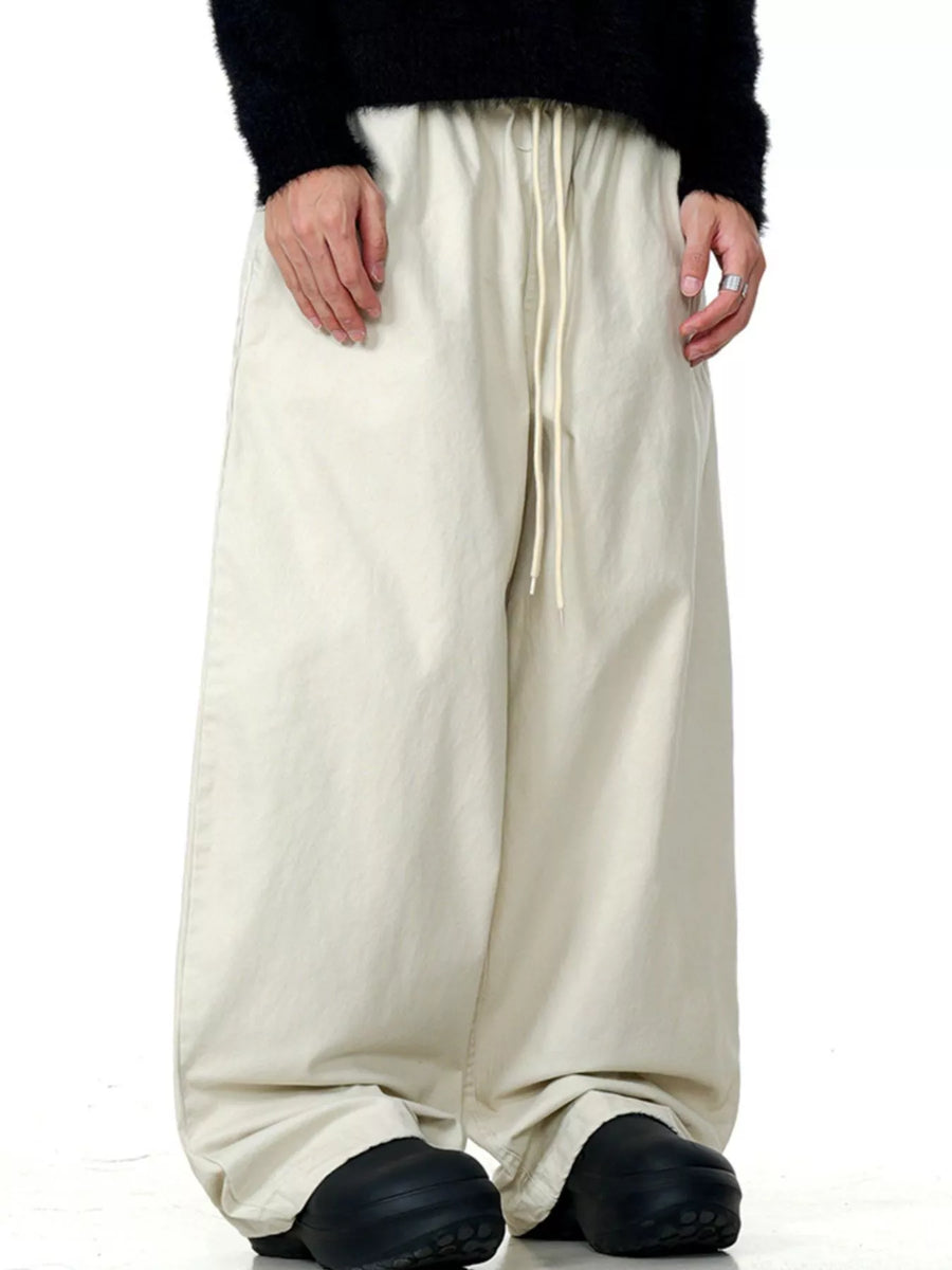 Relaxed wide-leg trousers in light beige with a drawstring waist and casual fit.