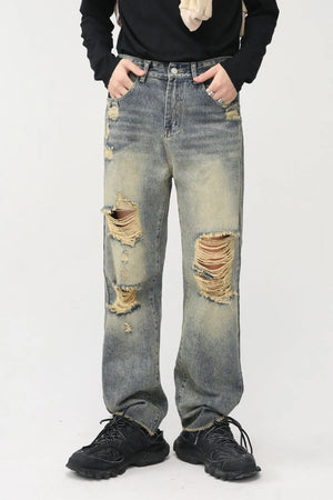 Distressed baggy denim jeans in medium wash with shredded knees and frayed hems.