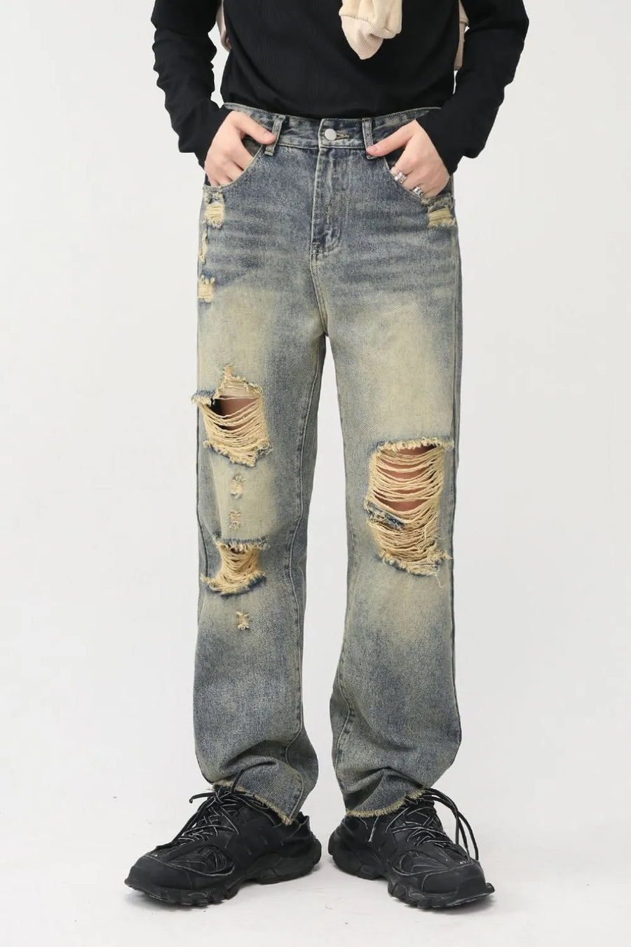 Distressed baggy denim jeans in medium wash with shredded knees and frayed hems.