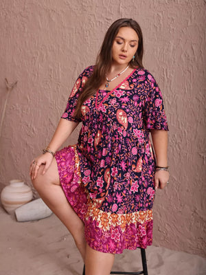 Plus-size navy floral flutter dress with ruched bodice and tiered hem.