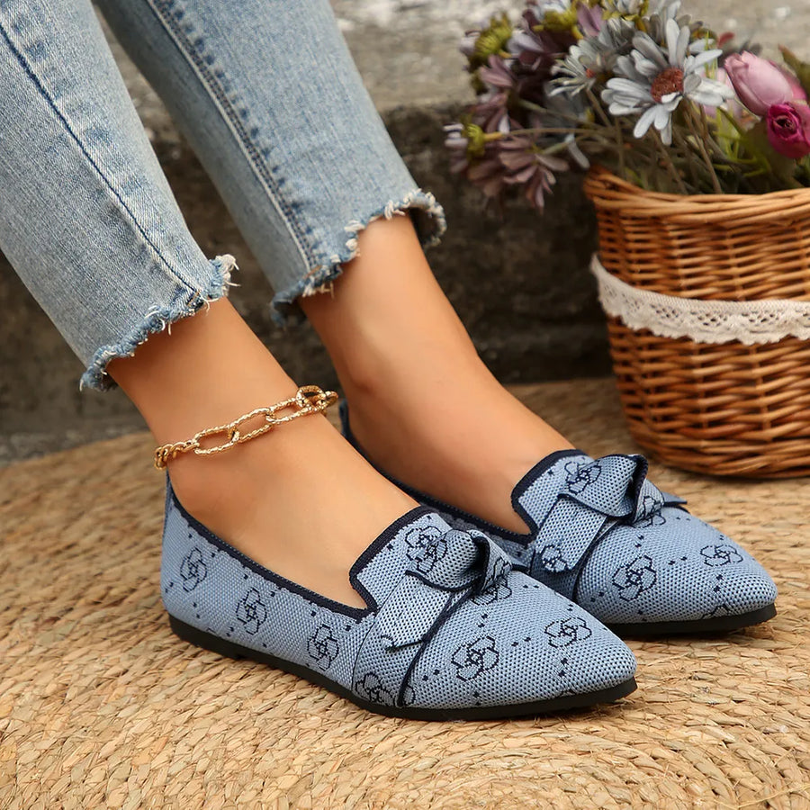 Pastel blue knitted pointed flats with bow detail and all-over floral pattern.