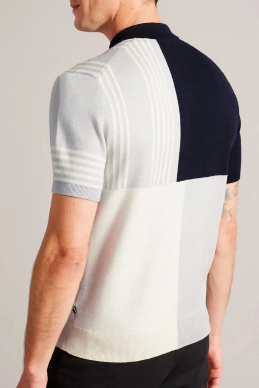 Geometric knit polo with zip neck in light blue, white, and navy colorblock with vertical stripes.