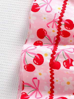 Toddler pink cotton blend dress with cherry print, bows, flowers, and red ric rac trim.