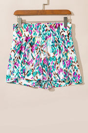 White running shorts with colorful brushstroke print and elastic waistband.