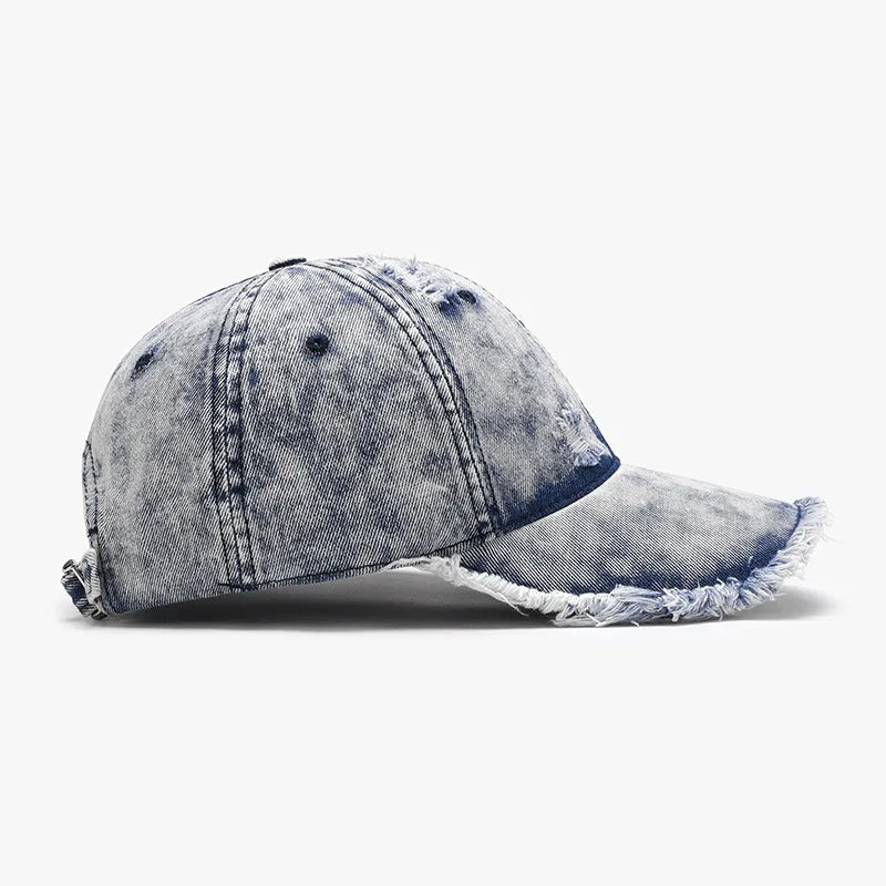 Acid wash frayed denim baseball cap in dark blue with distressed details and raw edge brim.