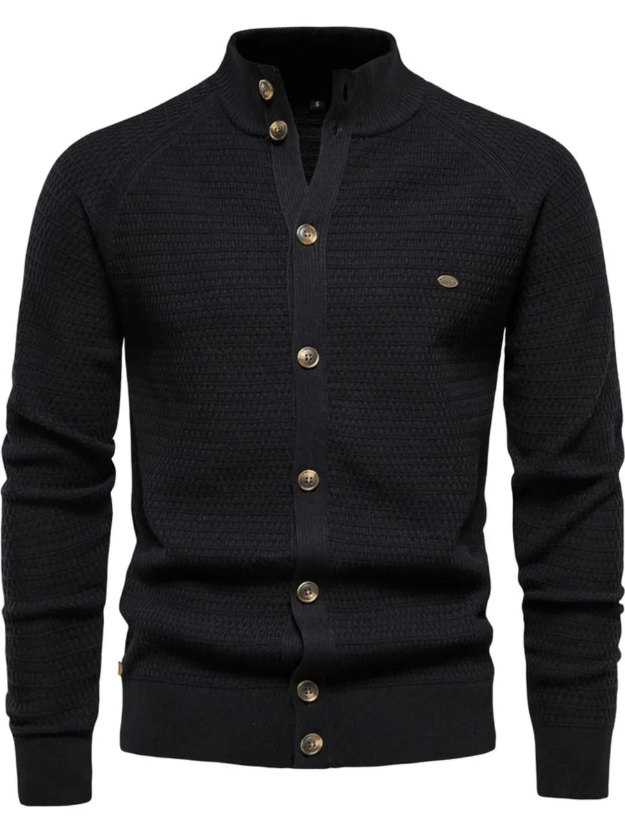 Black textured knit stand collar cardigan with button closure and raglan sleeves.