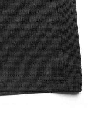Black textured knit jumpsuit detail showing waffle weave fabric and hem.