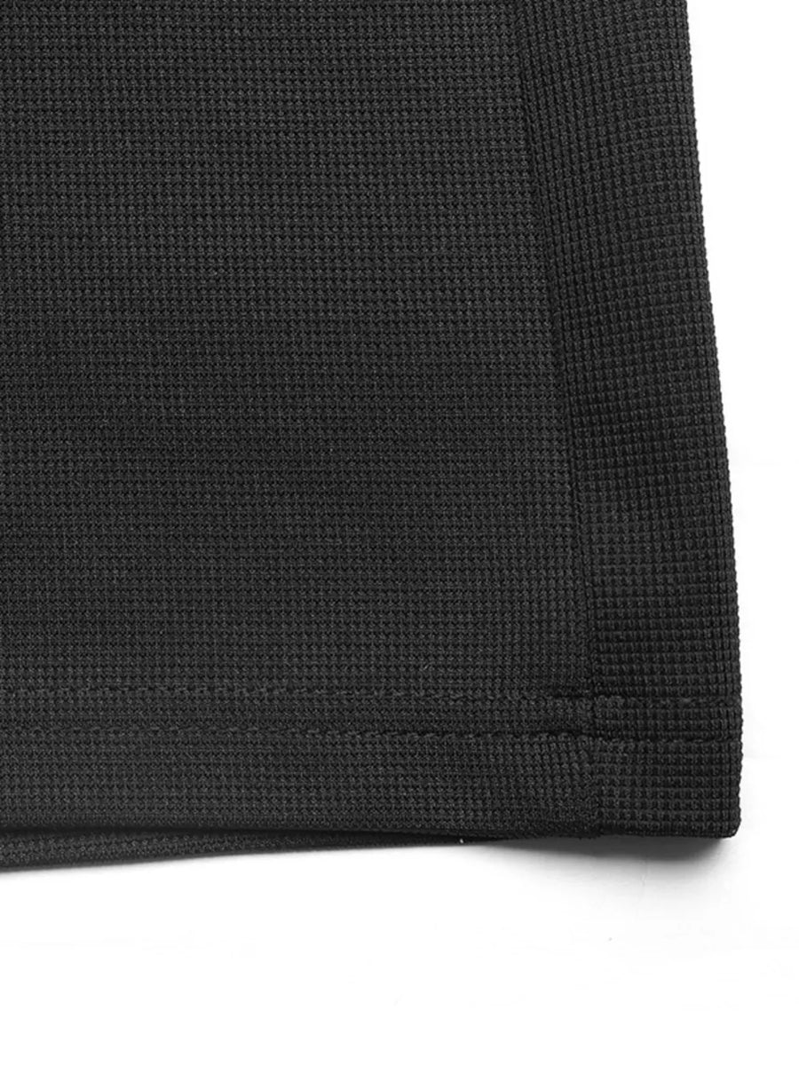 Black textured knit jumpsuit detail showing waffle weave fabric and hem.