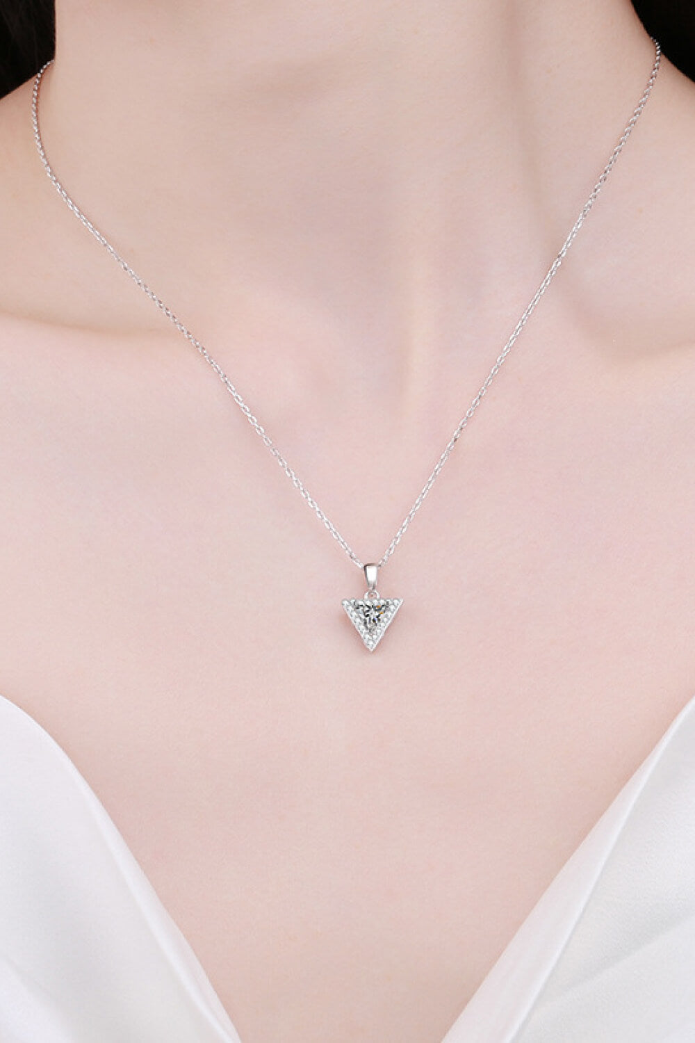 Silver geometric halo moissanite necklace with triangle pendant on a delicate chain.