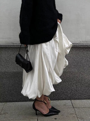 White balloon midi skirt with a black knit sweater and black chain strap handbag.