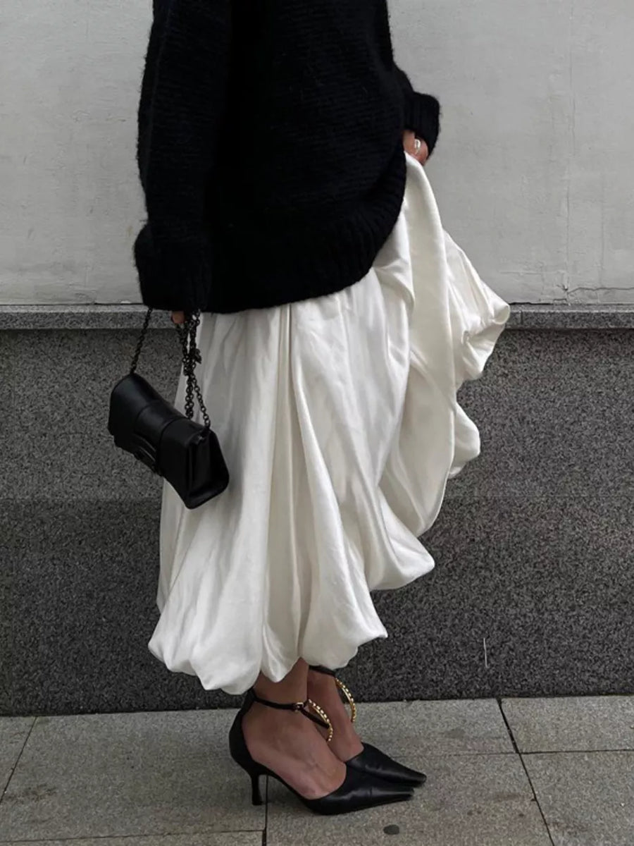 White balloon midi skirt with a black knit sweater and black chain strap handbag.